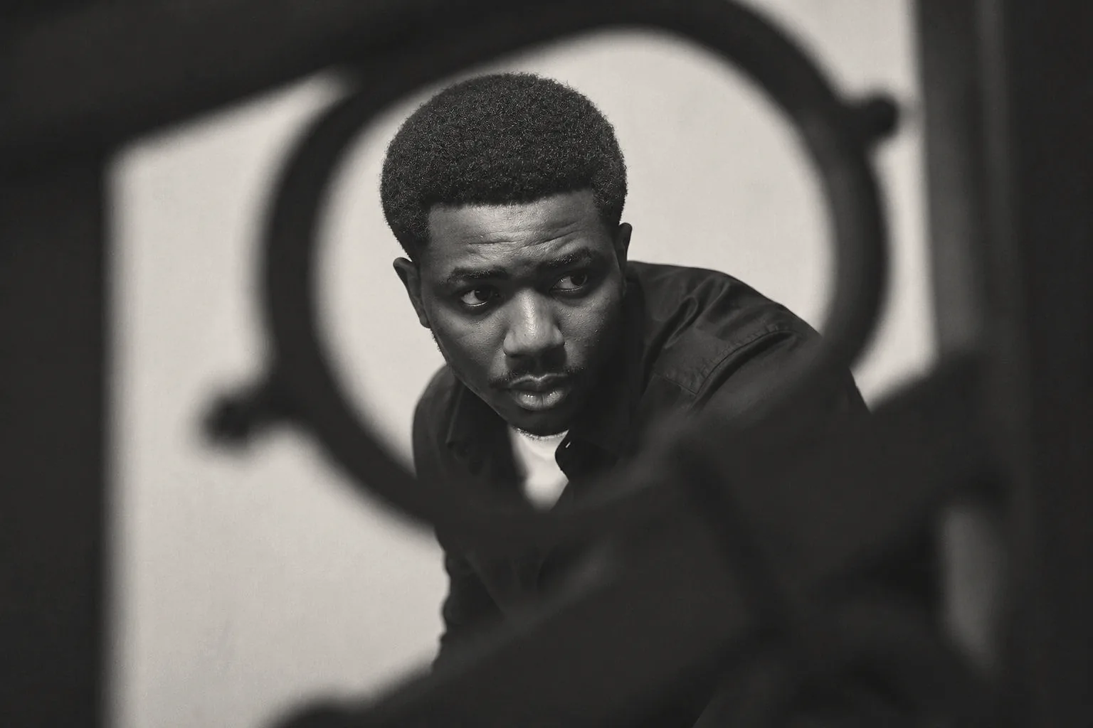 Aristide KARBOU in black and white, seen through a wrought-iron ring
